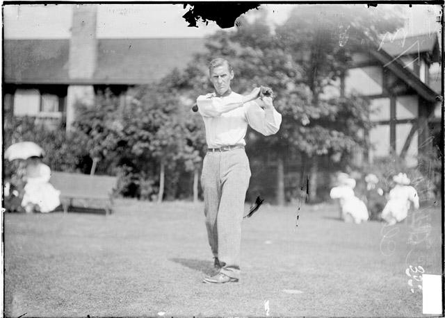Black and white photo of a man swinging a golf club.